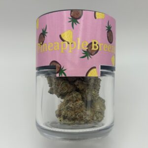 An eighth of the THCA flower Pineapple Breeze in a glass jar from Dama Botanicals.